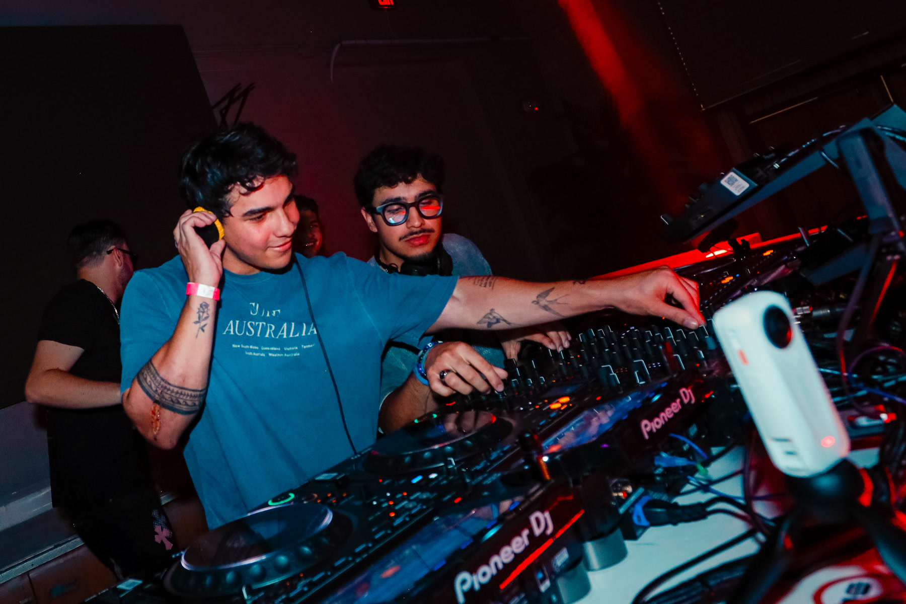 Two DJs mixing together at the decks