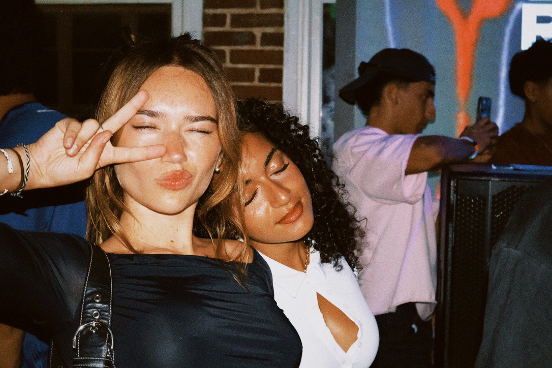 Two friends posing together beside the dance floor